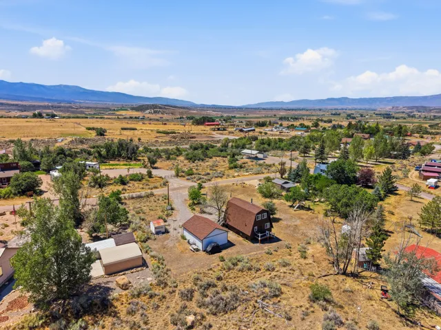 Aerial perspective showcasing a barn-style residence with a brown roof, a detached garage, and a secondary outbuilding