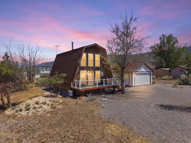 A-frame residence with a prominent front balcony and a detached single-car garage