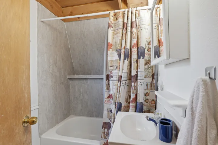 White bathtub with gray patterned shower surround and built-in shelf