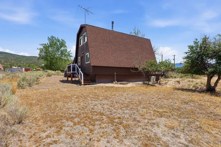 A-frame style residence featuring a brown exterior, a brown shingle roof, and white-trimmed windows