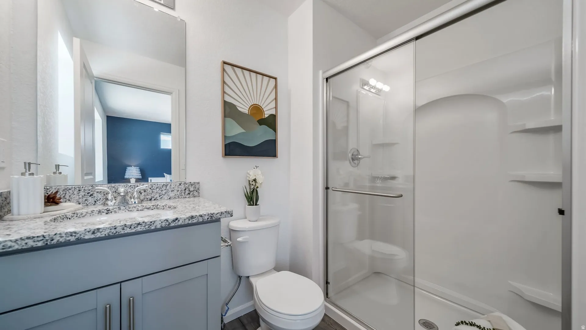 Bathroom featuring a gray vanity with double-door cabinetry, granite countertop, and a single basin sink with a chrome faucet