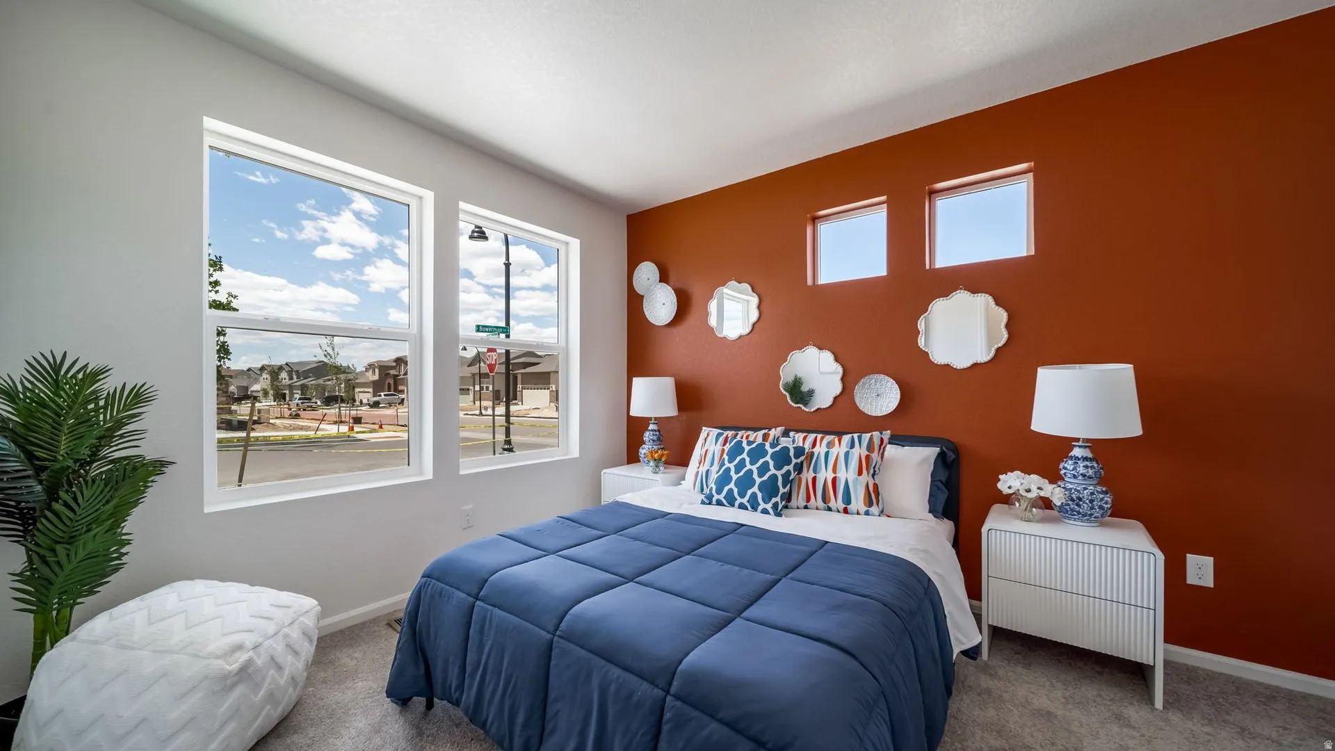 Bedroom featuring a warm accent wall, dual windows, and plush carpeting