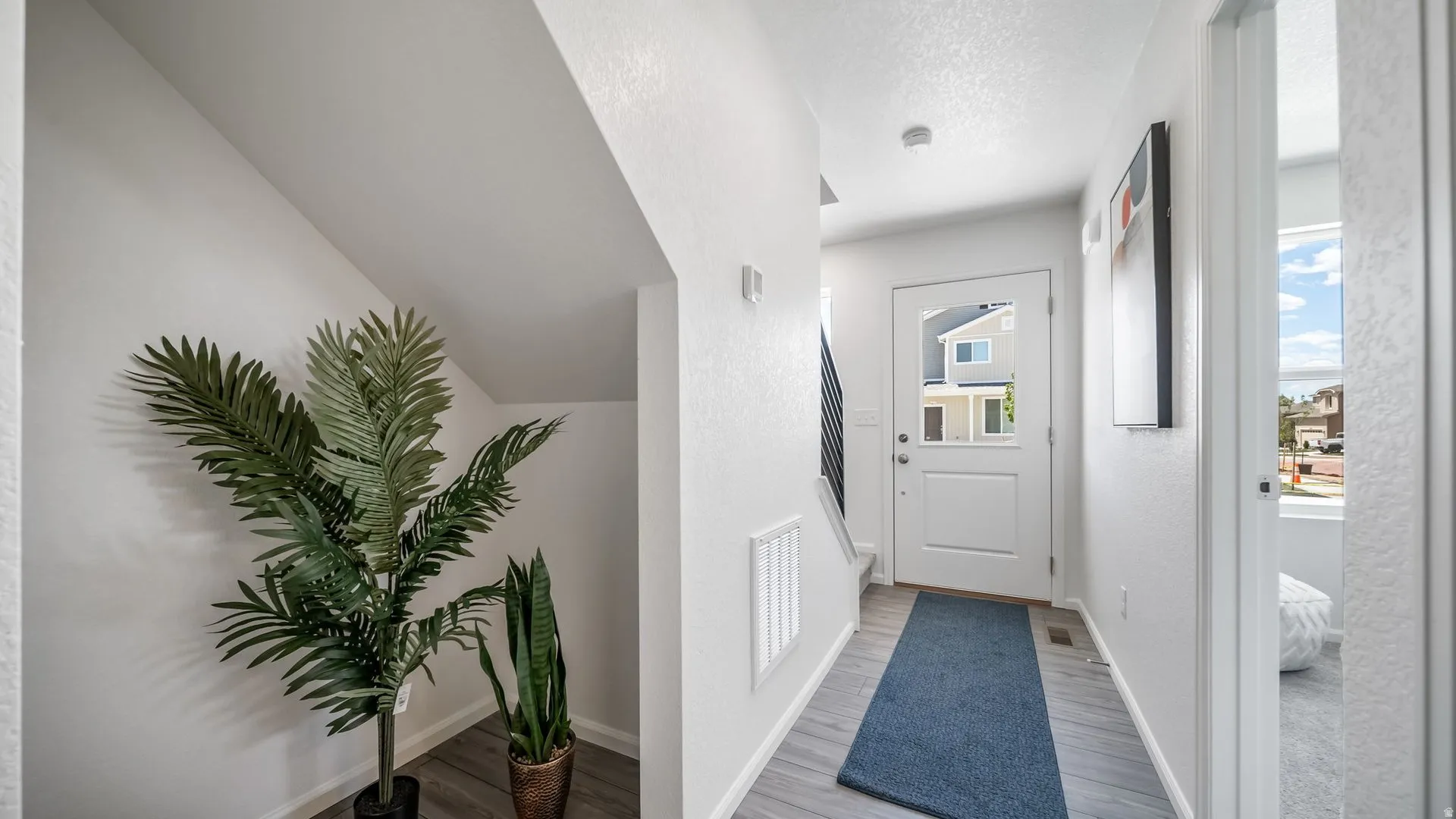 Entryway featuring light wood-finish flooring, a white paneled door with an upper glass insert, and a staircase with dark railings
