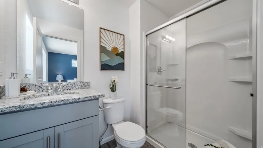 Bathroom featuring a gray vanity with double-door cabinetry, granite countertop, and a single basin sink with a chrome faucet