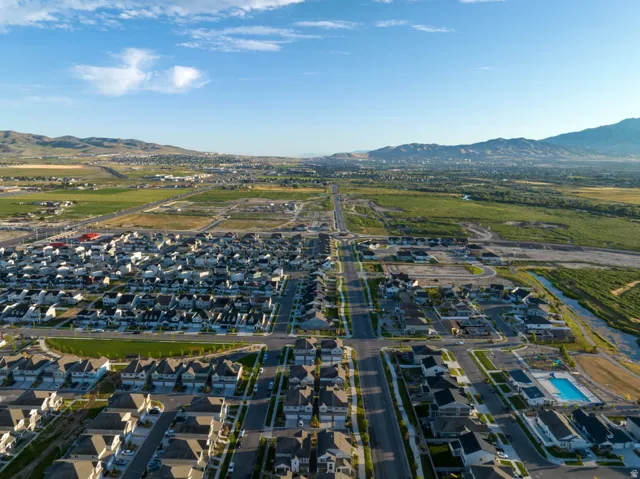 Expansive aerial perspective showcasing a residential community with numerous single-family homes, clear streets, and a prominent community swimming pool