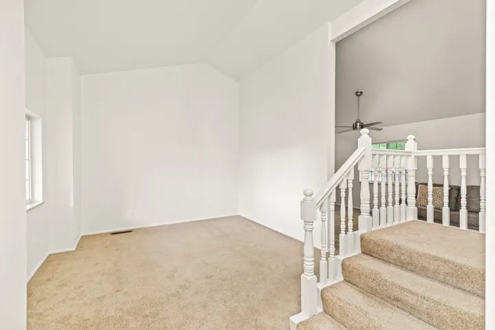 Carpeted staircase with white painted wood balusters and handrail