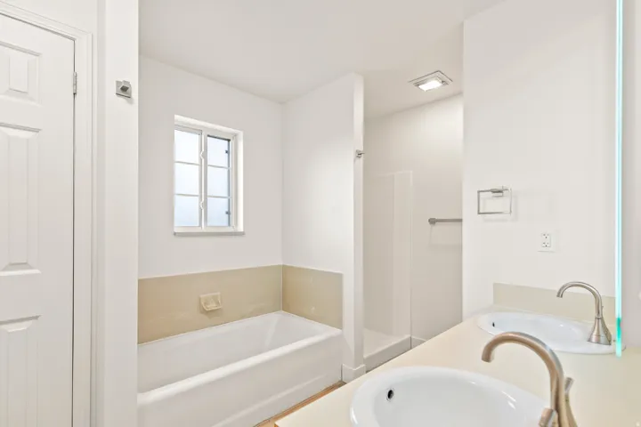 Bathroom featuring a dual vanity, built-in bathtub, and separate shower enclosure