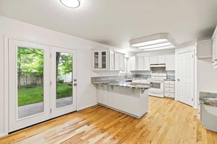 Kitchen featuring white cabinetry, granite countertops, and wood-finish flooring