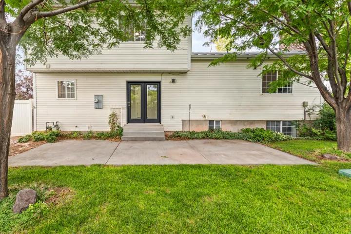 Rear exterior with white siding and a concrete patio