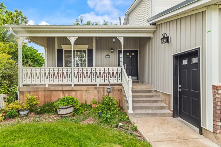 Inviting front porch featuring intricate white spindle railings, dark accent shutters, and a prominent dark entry door