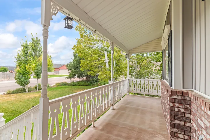Covered front porch featuring decorative white railings and columns