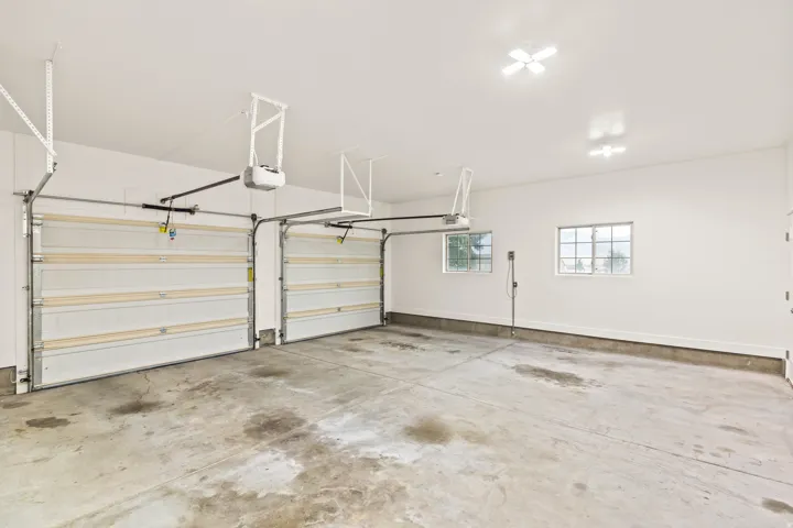 Spacious two-car garage featuring a concrete floor, two automatic garage door openers, and two multi-pane windows