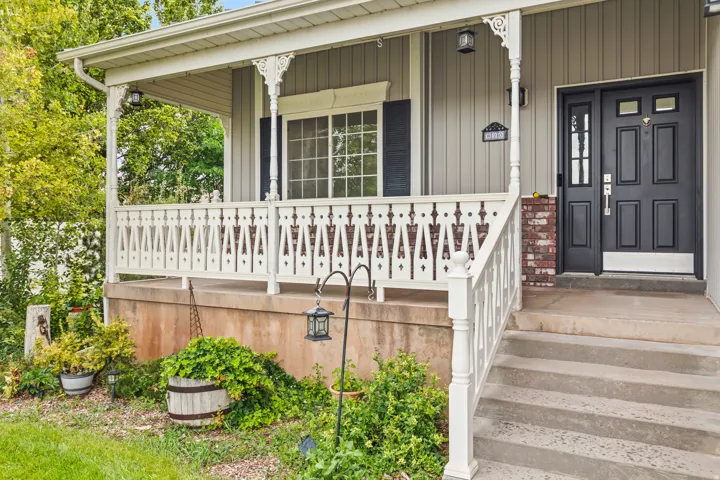 Covered front porch featuring decorative white railings and columns