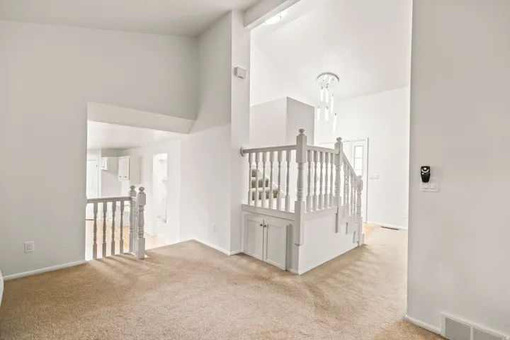 Entryway featuring a grand staircase with white balusters, built-in storage cabinets, and a contemporary chandelier