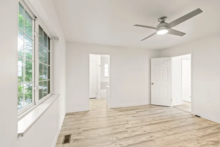 Room featuring wood-finish flooring, a contemporary ceiling fan with integrated lighting, and white paneled doors