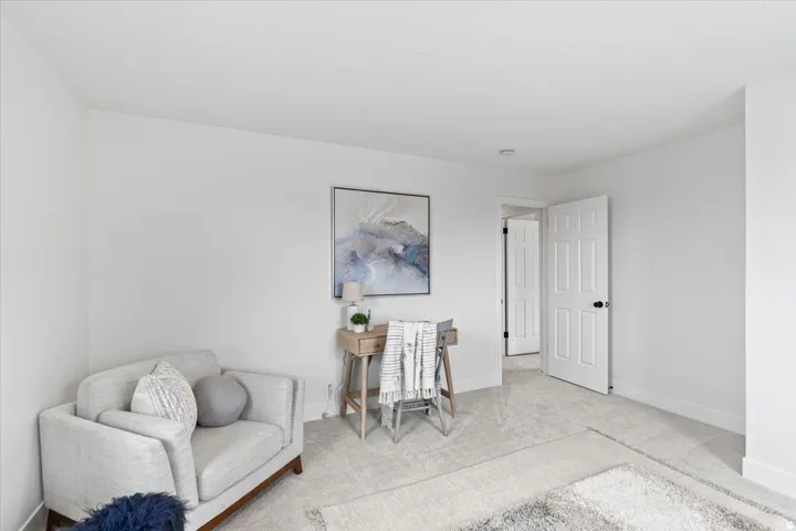 Carpeted room with a paneled interior door, white baseboards, and neutral wall finishes