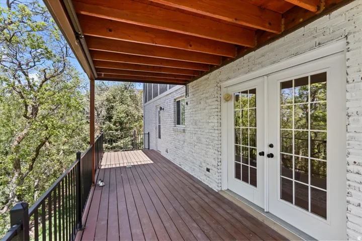 Spacious outdoor deck featuring wood-finish flooring, black metal railings, and a natural wood-toned ceiling