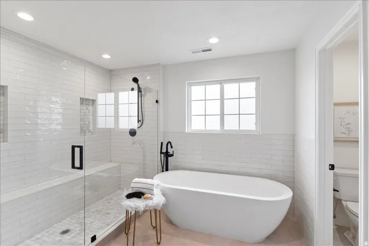 White subway tile shower enclosure with built-in bench and recessed shelving