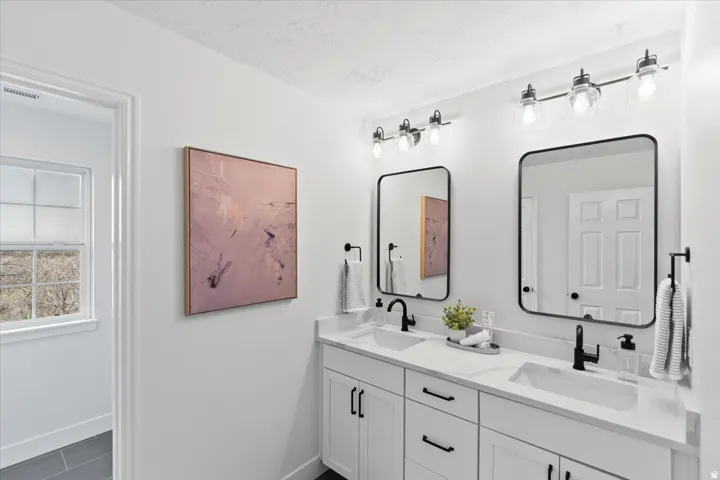 Dual vanity featuring white shaker-style cabinetry, white countertops, and matte black fixtures