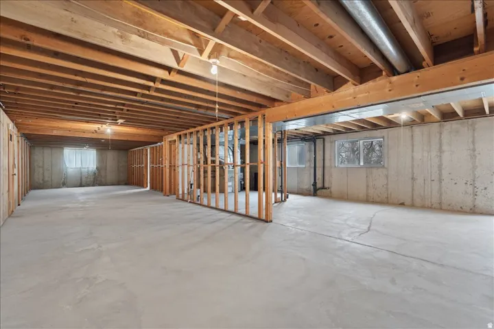 Unfinished basement featuring exposed wood joists and concrete flooring