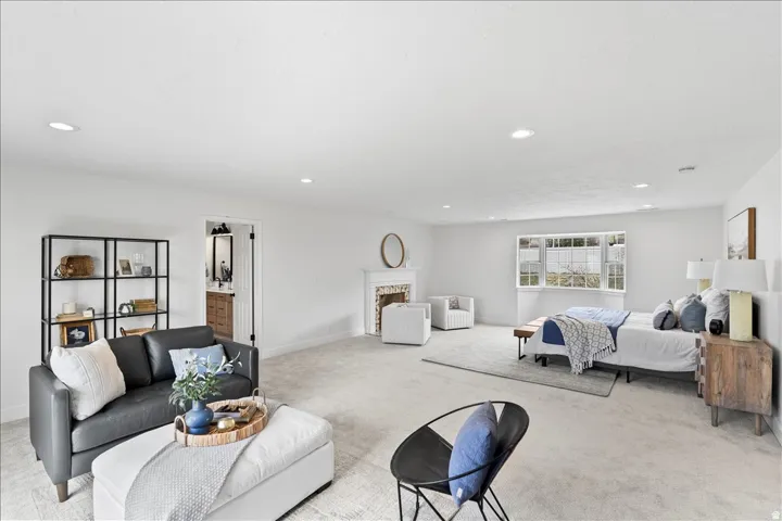 Spacious room with light neutral carpeting, recessed lighting, white walls, and a large window