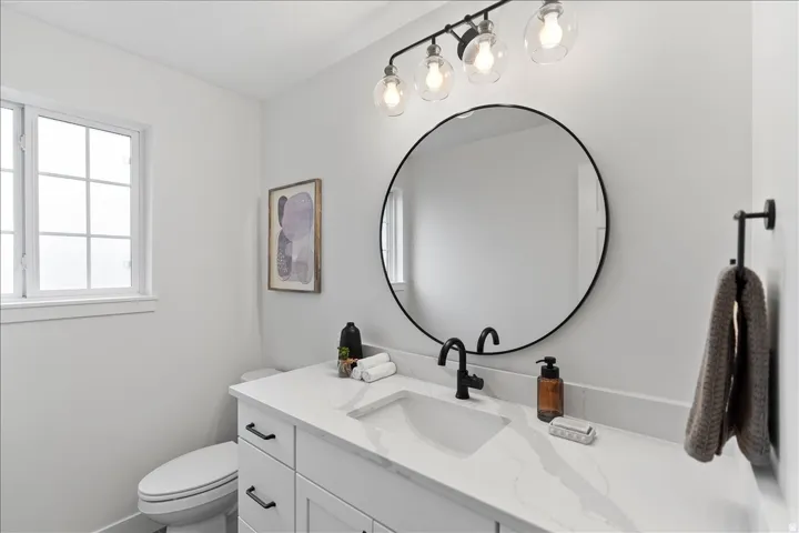 Bathroom featuring a white vanity with integrated sink, quartz-finish countertop, and matte black fixtures