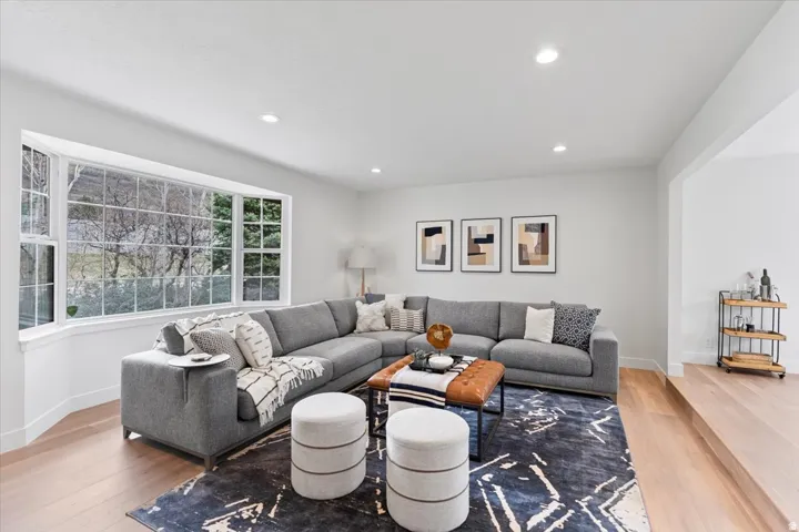Spacious interior with expansive bay window, recessed lighting, light wood-finish flooring, and a defined open archway