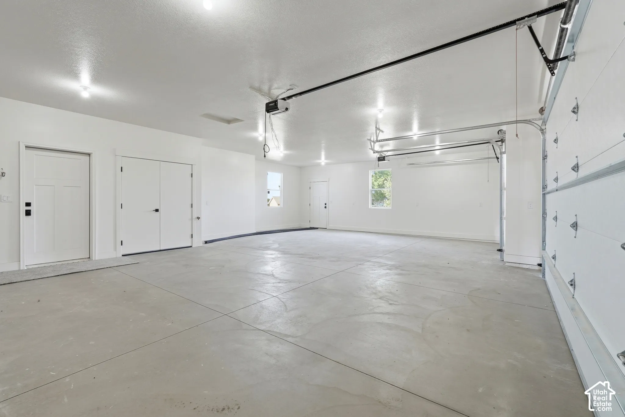 Spacious garage with light gray concrete flooring, white walls, and bright overhead lighting