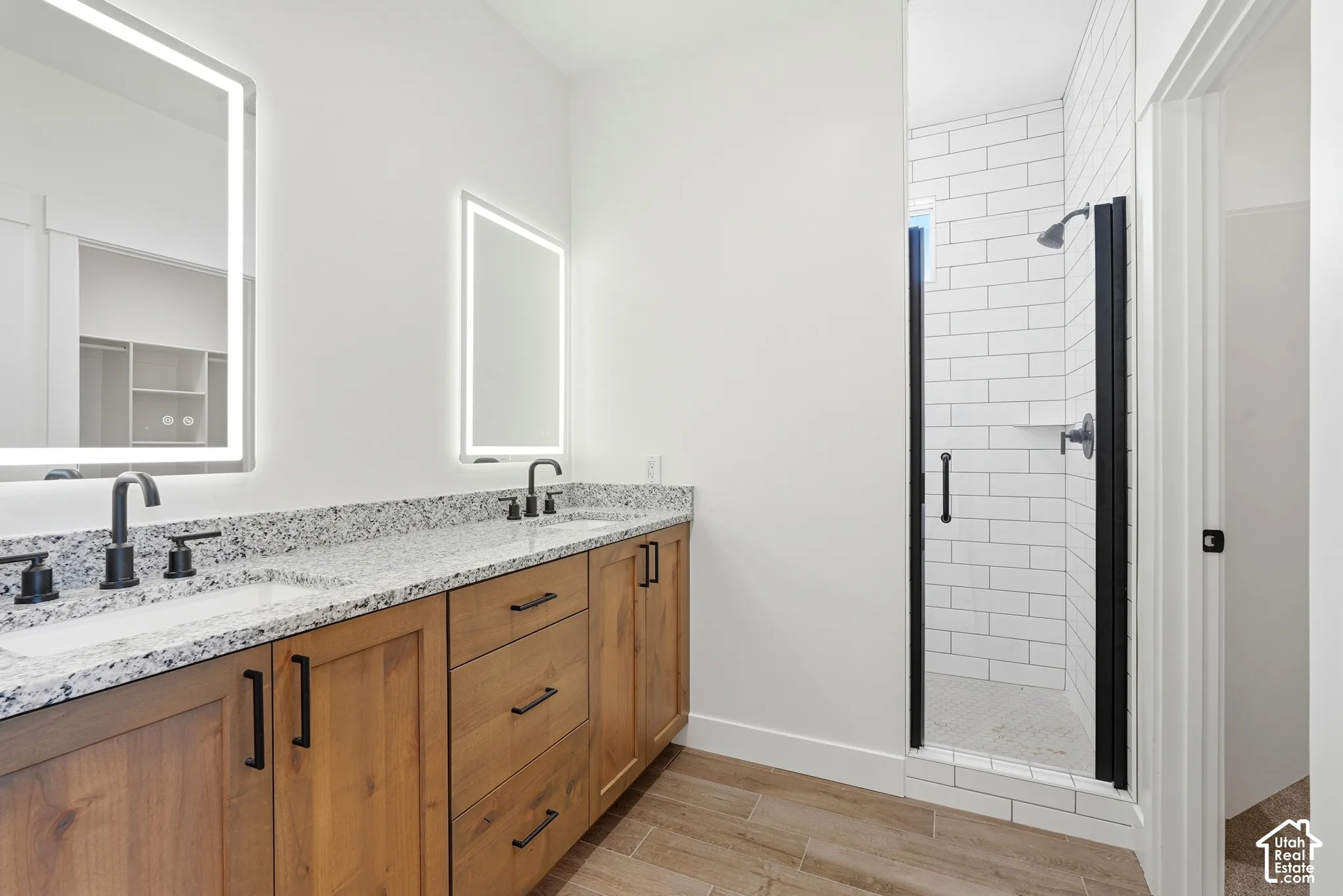 Dual vanity with granite countertops, wood-finish cabinetry, and matte black fixtures