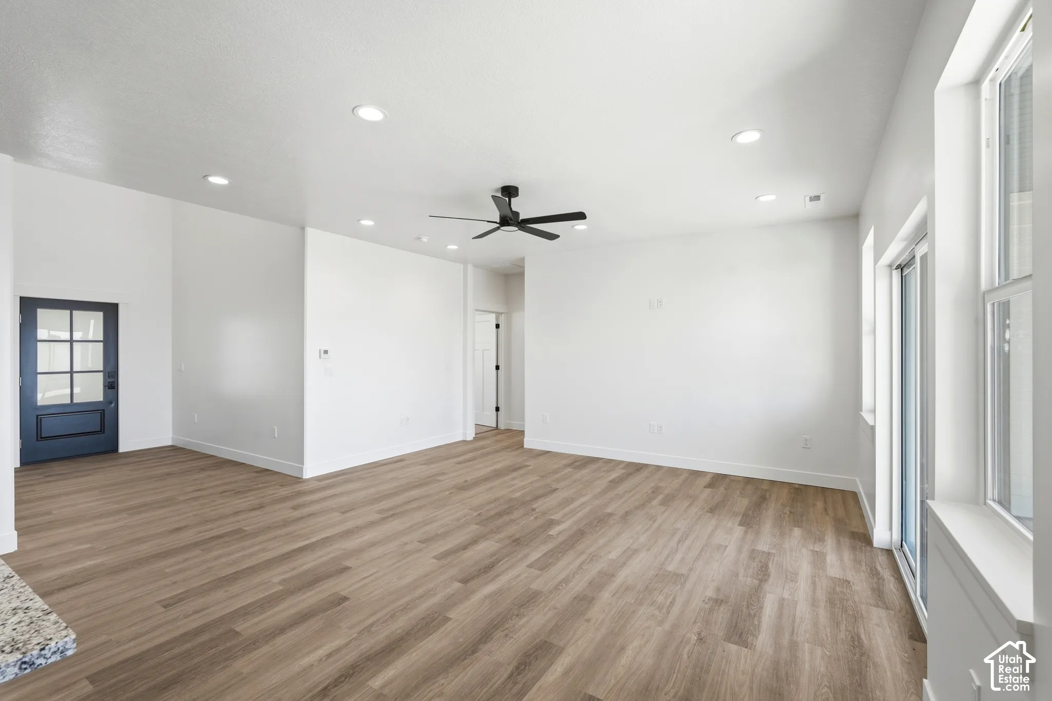 Open-concept living space with wood-finish flooring, recessed lighting, and a modern ceiling fan