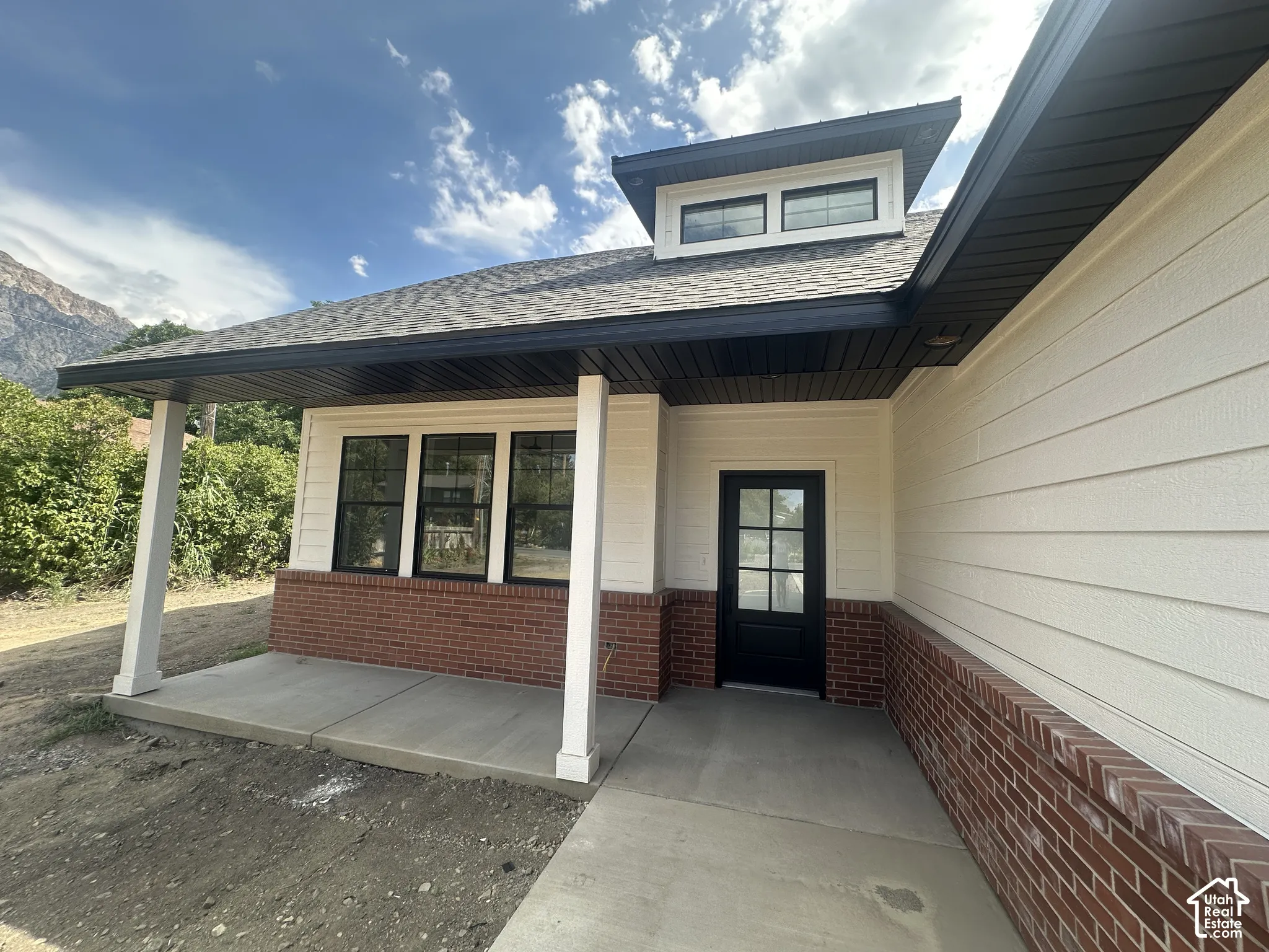 Contemporary exterior featuring white horizontal siding and brick accents