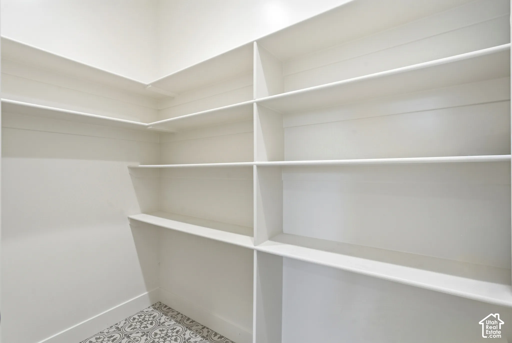 Built-in shelving with multiple levels, white walls, and a patterned floor