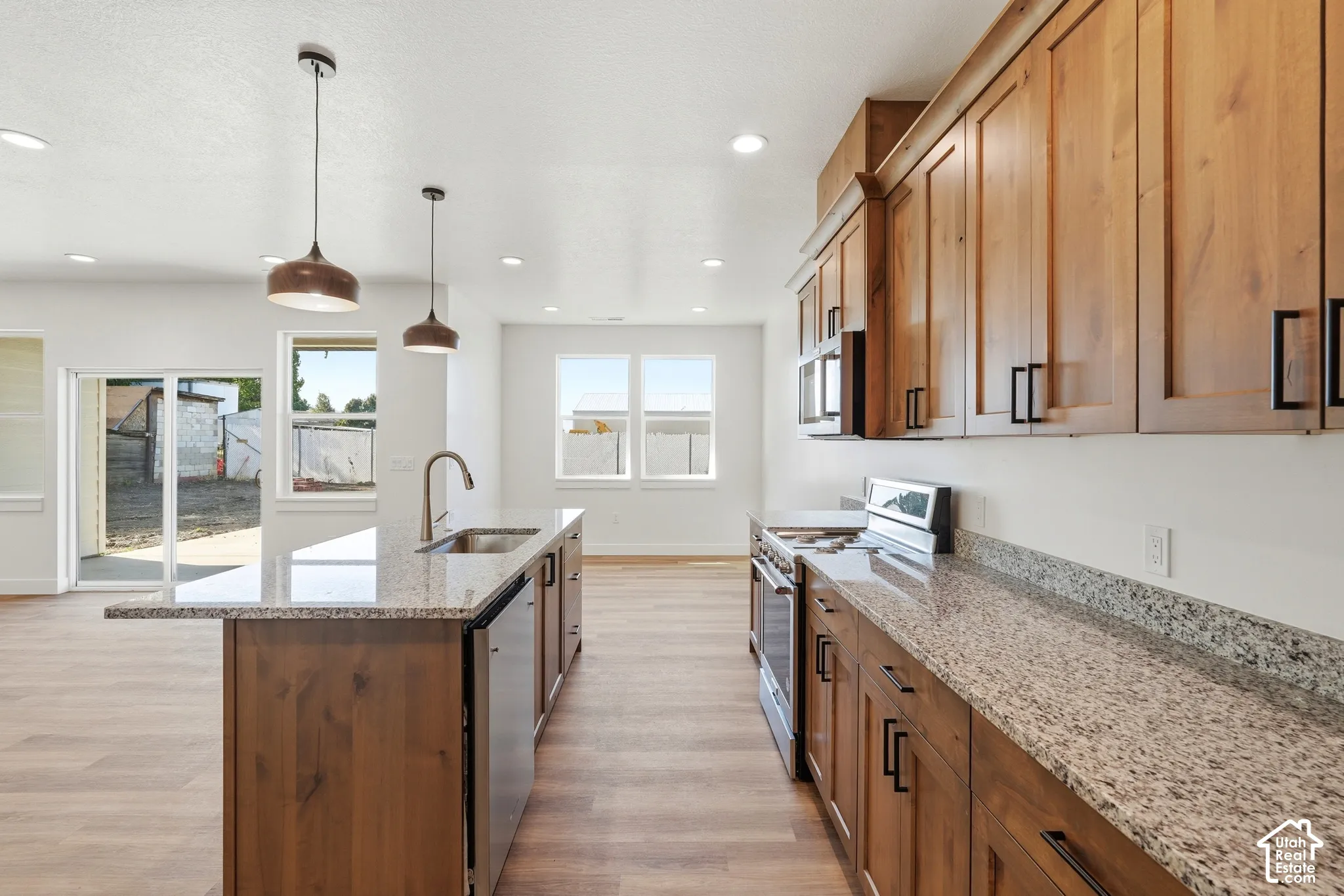 Kitchen featuring wood-finish cabinetry, granite countertops, stainless steel appliances, and a large center island with a sink