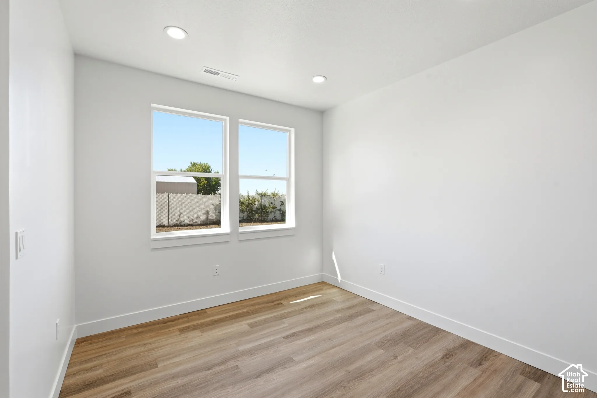 Wood-finish flooring, recessed lighting, and white walls