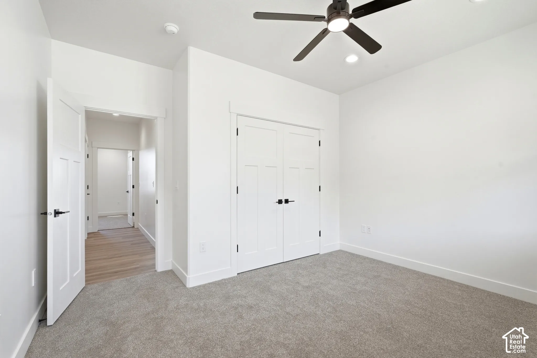 Recessed lighting, ceiling fan, white paneled doors, carpet flooring, and wood-finish flooring in the hallway