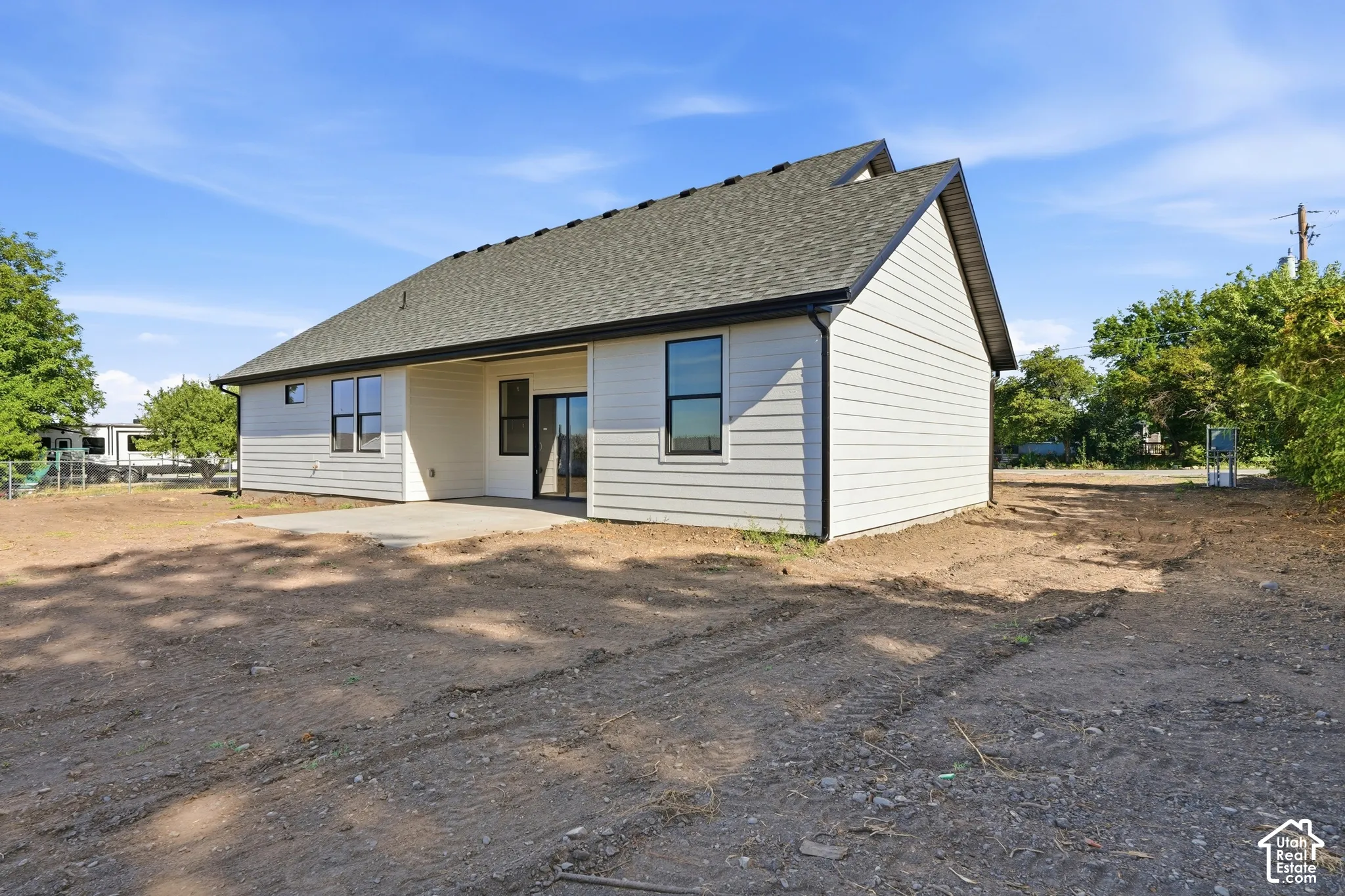 Rear exterior showcasing horizontal siding, a gabled roofline, a concrete patio, and a sliding glass door