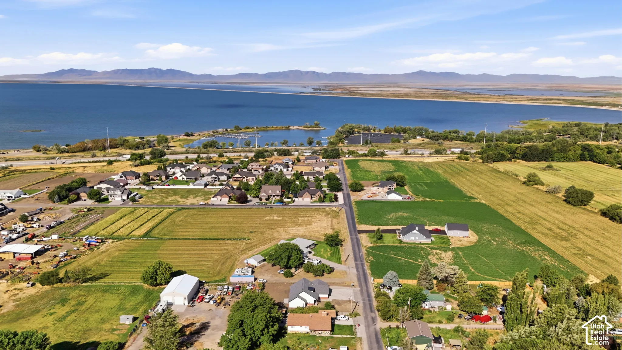 Expansive waterfront property featuring a large body of water, distant mountain range, and surrounding green fields