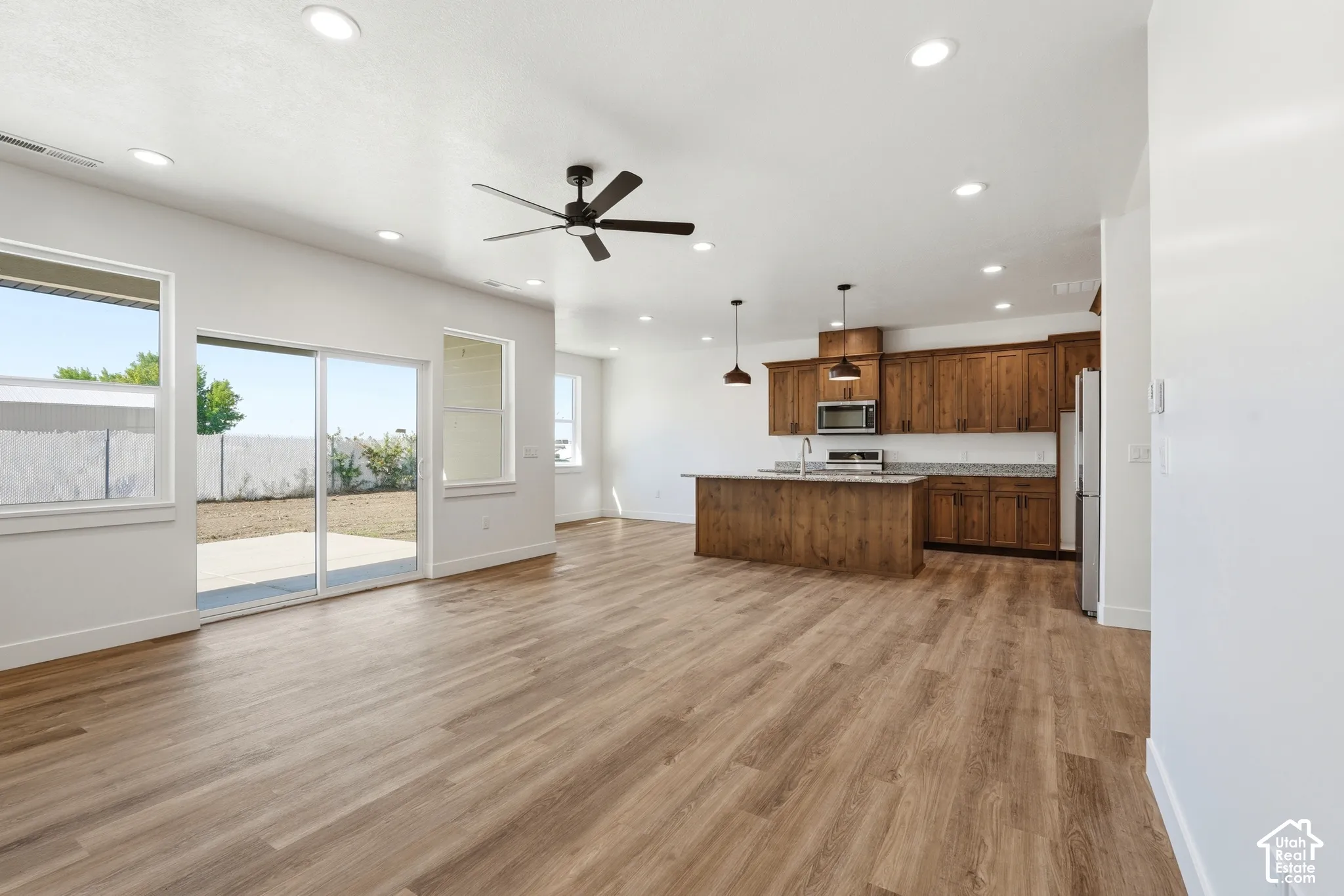 Open-concept living area featuring wood-finish flooring, recessed lighting, and a ceiling fan