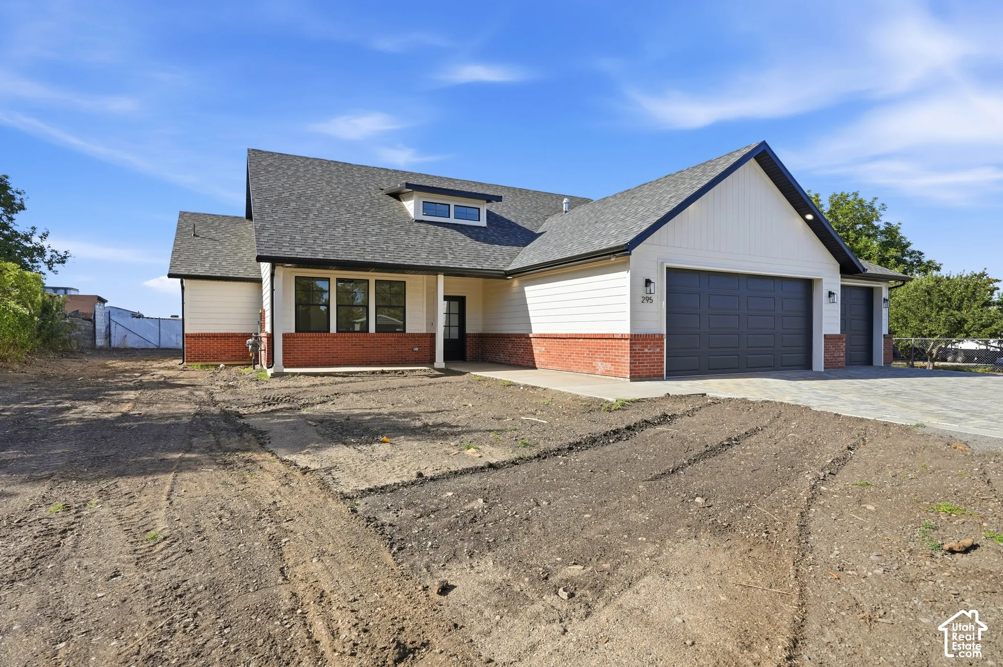 Contemporary exterior featuring a combination of brick and siding, a dark asphalt shingle roof, dark-framed windows, and a multi-car attached garage