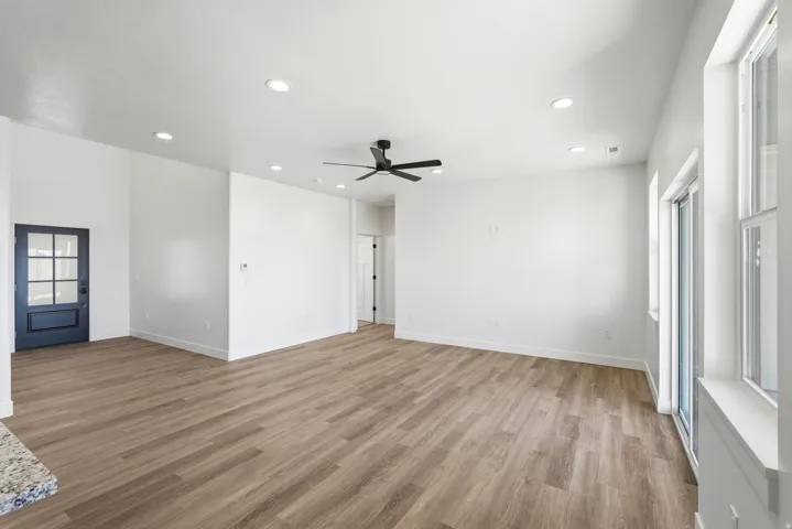 Expansive open-concept living space with wood-finish flooring, recessed lighting, and a modern ceiling fan