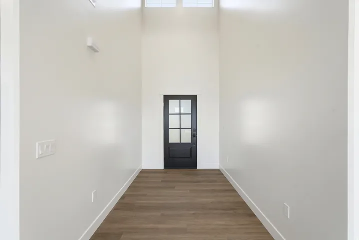 Two-story entryway with wood-finish flooring, white walls, and a black paneled door with glass inserts