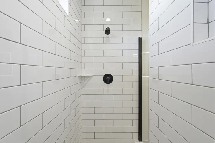 Shower enclosure with white subway tile, matte black fixtures, and a built-in shelf