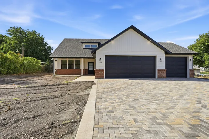 Modern farmhouse exterior with white siding and dark trim, featuring a multi-car garage with dark paneled doors