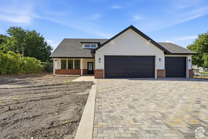Modern farmhouse exterior with white siding, brick accent and dark trim, featuring a three-car garage.