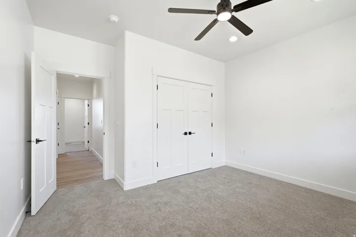 Recessed lighting, ceiling fan, white paneled doors, carpet flooring, and wood-finish flooring in the hallway