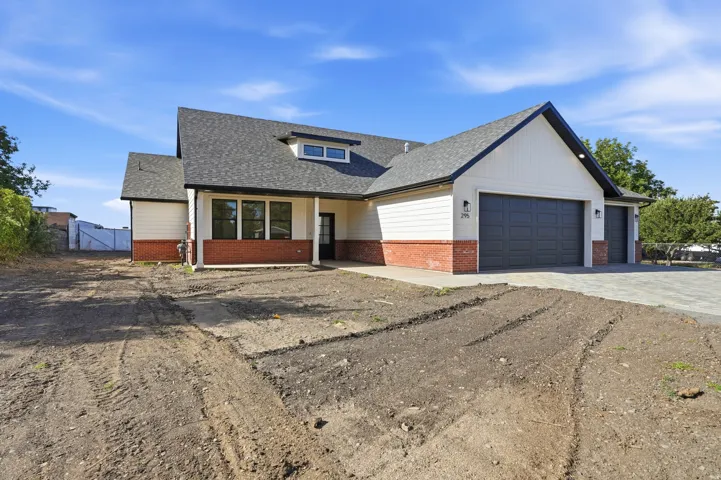 Contemporary exterior featuring a combination of brick and siding, a dark asphalt shingle roof, dark-framed windows, and a multi-car attached garage