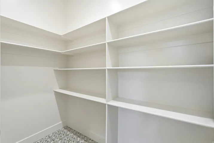 Built-in shelving with multiple levels, white walls, and a patterned floor