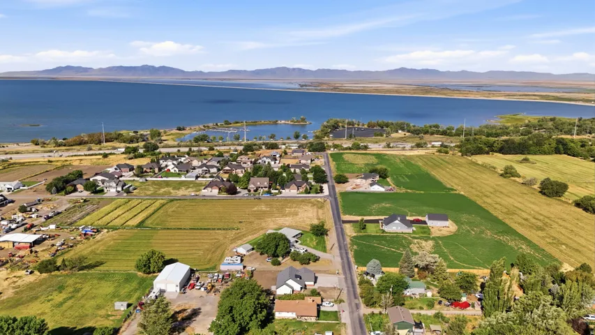Expansive waterfront property featuring a large body of water, distant mountain range, and surrounding green fields