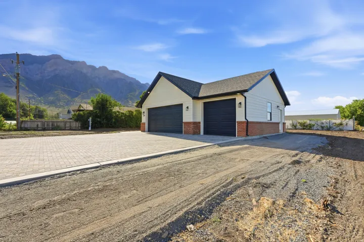 Cream siding exterior with brick veneer accent, two dark-toned garage doors, and a paved driveway