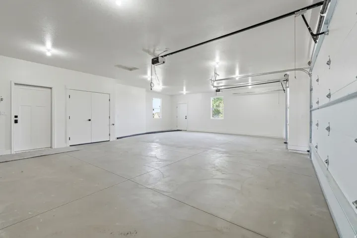 Spacious garage with light gray concrete flooring, white walls, and bright overhead lighting
